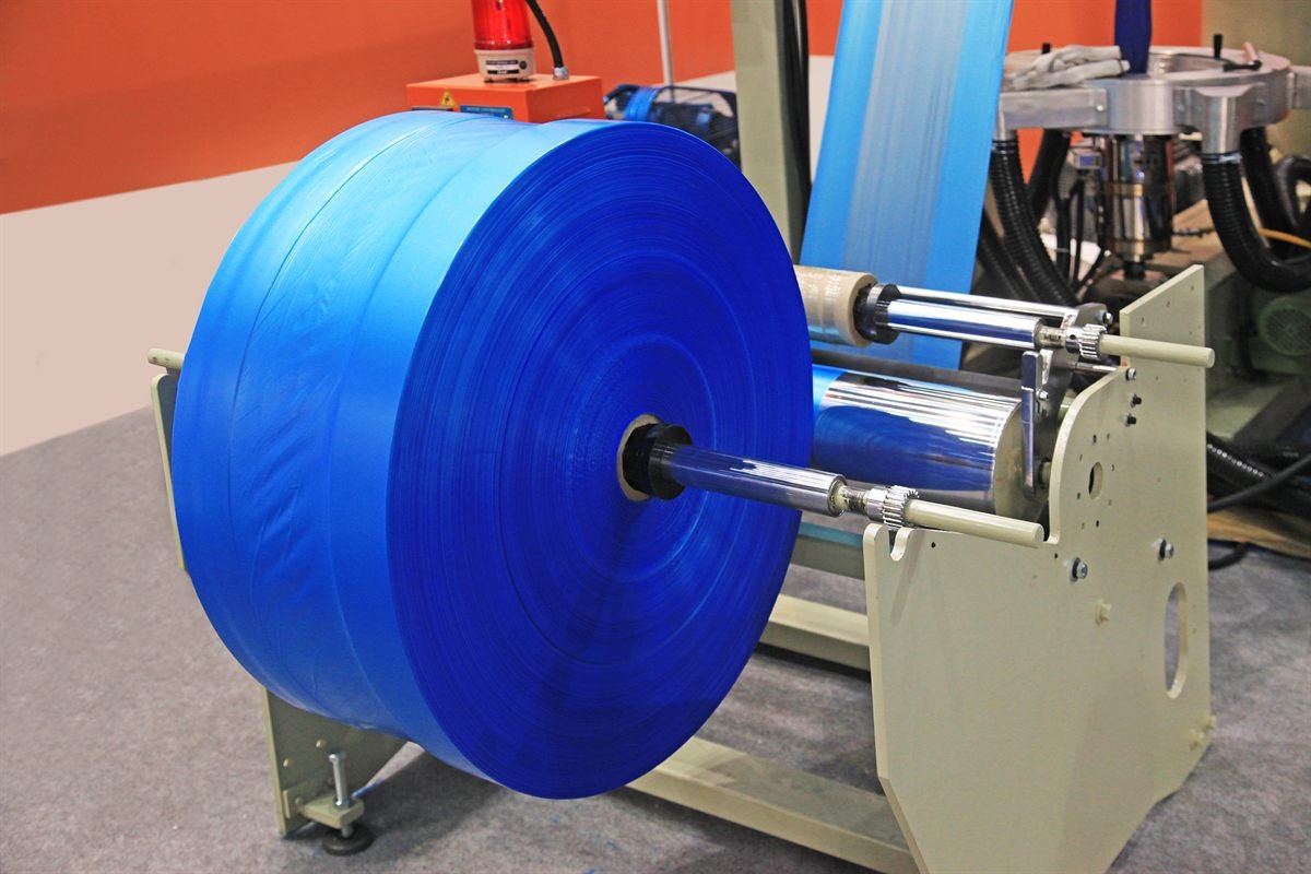 A roll of shrink sleeve film feeding into a sleeving machine